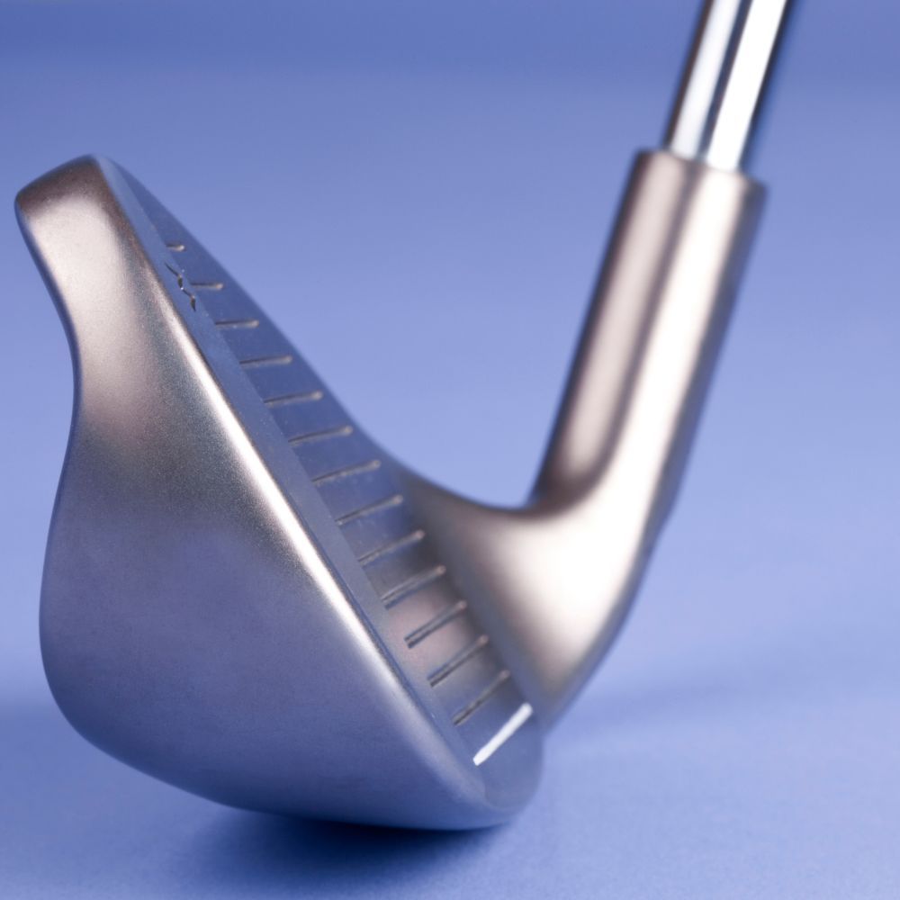 A golfer holding a sand wedge and a pitching wedge